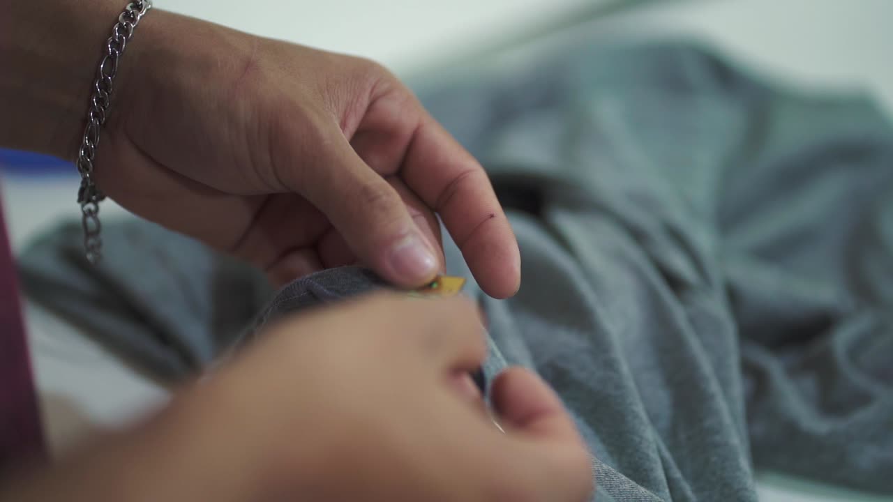 Close-up of Hispanic female seamstress measuring fabric for sewing garment in workshop. Argentina.