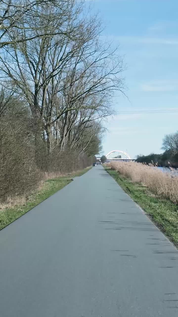 Lang recht pad langs een kanaal leidend naar een verre brug