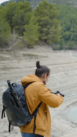 photographer exploring a dry landscape with camera and tripod
