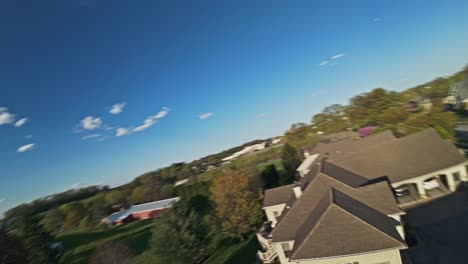 speed drone flight over luxury family houses during sunny day with blooming trees in spring, fpv shot at sunset time