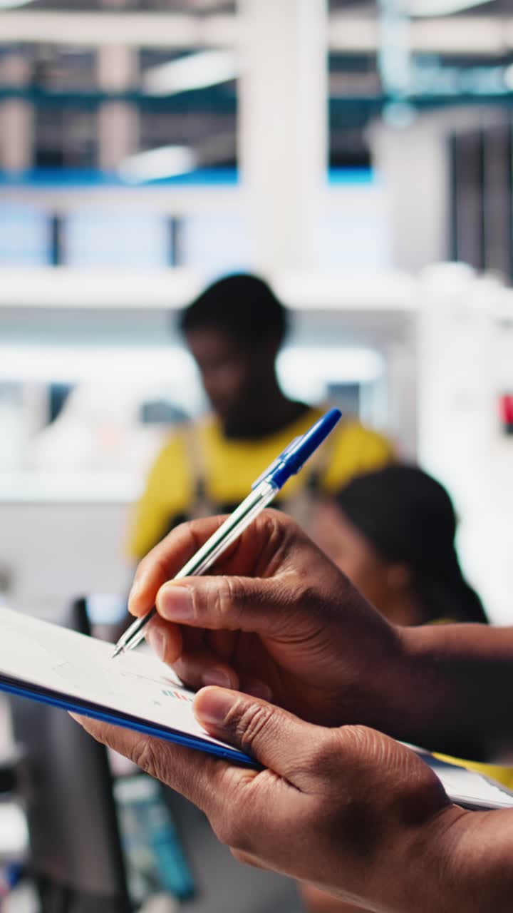 Vertical Video Black technician programs solar panel assembly line from desktop computer