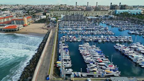 Drohnenaufnahme-Des-Yachthafens-Des-King-Harbor-Yacht-Club,-Der-Wellenbrechermauer-Von-Redondo-Beach-Und-Der-Gebäude-Am-Wasser,-Kalifornien,-USA