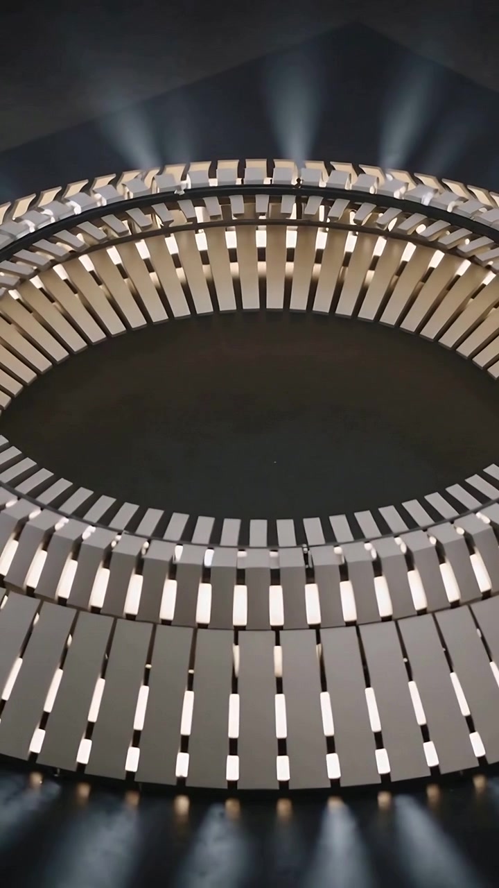 Vertical video: Pulsing dual-row ring slats emitting upward beams after LED pulse in dark studio
