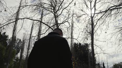 a man walking alone through a forest, backlit with a mysterious and moody feeling