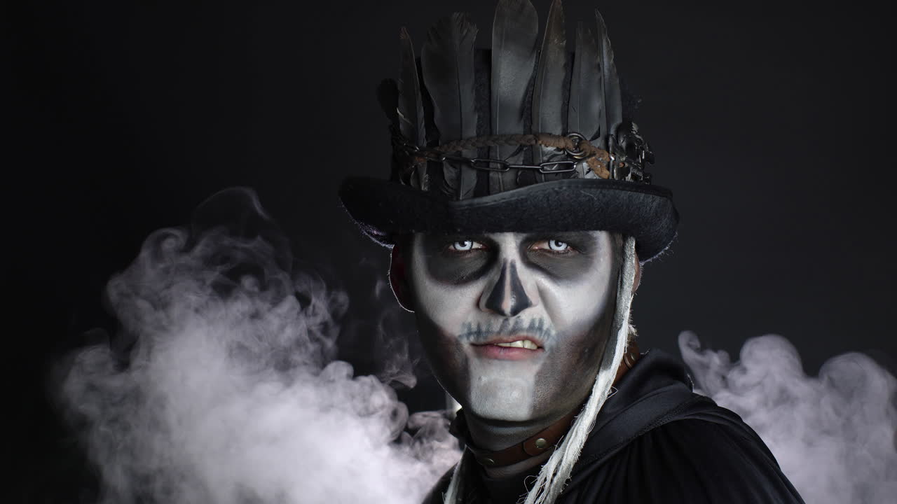 끔찍한 할로윈 골격 메이크업을 가진 악의적인 남자가 빛이 그 위에 떨어지면 어에서 나타납니다.