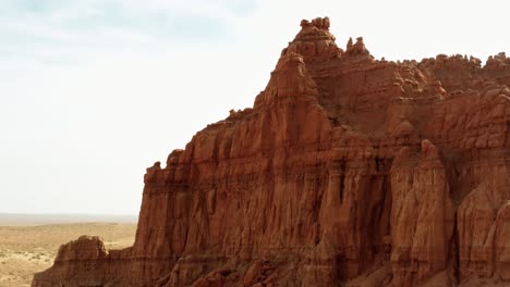 gorgeous trucking left aerial drone shot of the beautiful goblin valley utah state park passing a large red rock formation revealing a valley with looming red rock butte's on a warm sunny summer day