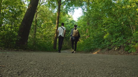 un hombre y una mujer caminan juntos por un camino en el bosque.