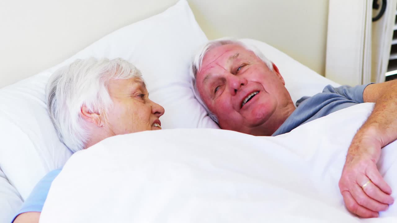 una pareja feliz interactuando entre sí mientras se acuestan en la cama.