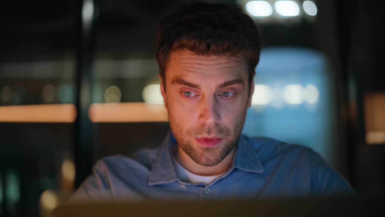 Closeup tired manager looking laptop at dark office. Overworked freelancer