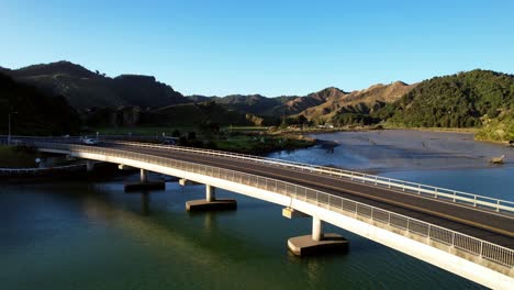 aerial shot of small truck crossing a bridge over a river