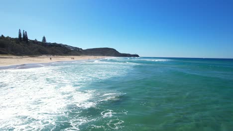 People-Walking-In-The-Sandy-Shoreline-Of-Sunshine-Beach-On-A-Sunny-Day-In-Noosa,-Queensland,-Australia