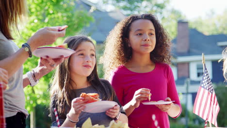 Girls stand eating pizza with neighbours at a block party