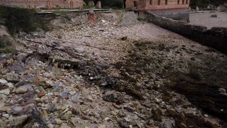 Tilt-up-from-rocky-Porth-Wen-beach-to-industrial-brickwork-factory-coastal-ruins