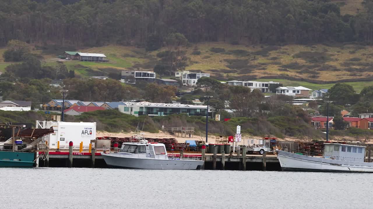 Boats maneuver near a pier on Great Ocean Road, Australia. Overcast lighting and steady camera capture the serene coastal environment