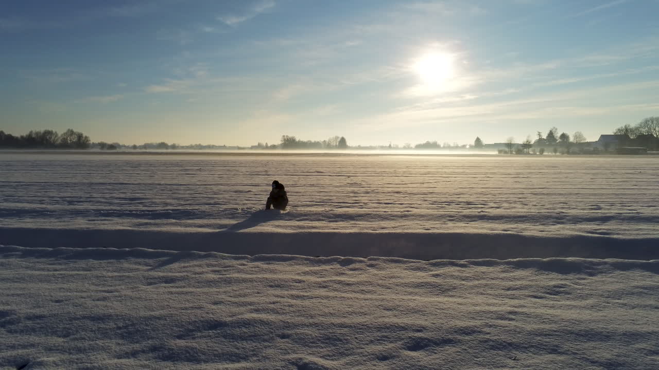 Ragazzino che gioca nella neve su un grande campo