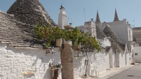 Trulli-Blancos-En-Alberobello-Con-Techo-De-Piedra-Y-Plantas-Delante-De-La-Puerta