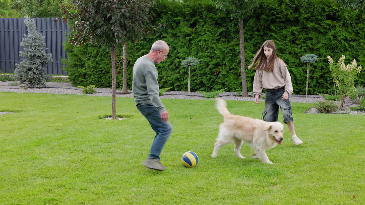 Nonno attivo che gioca a calcio con la nipote e il cane in giardino