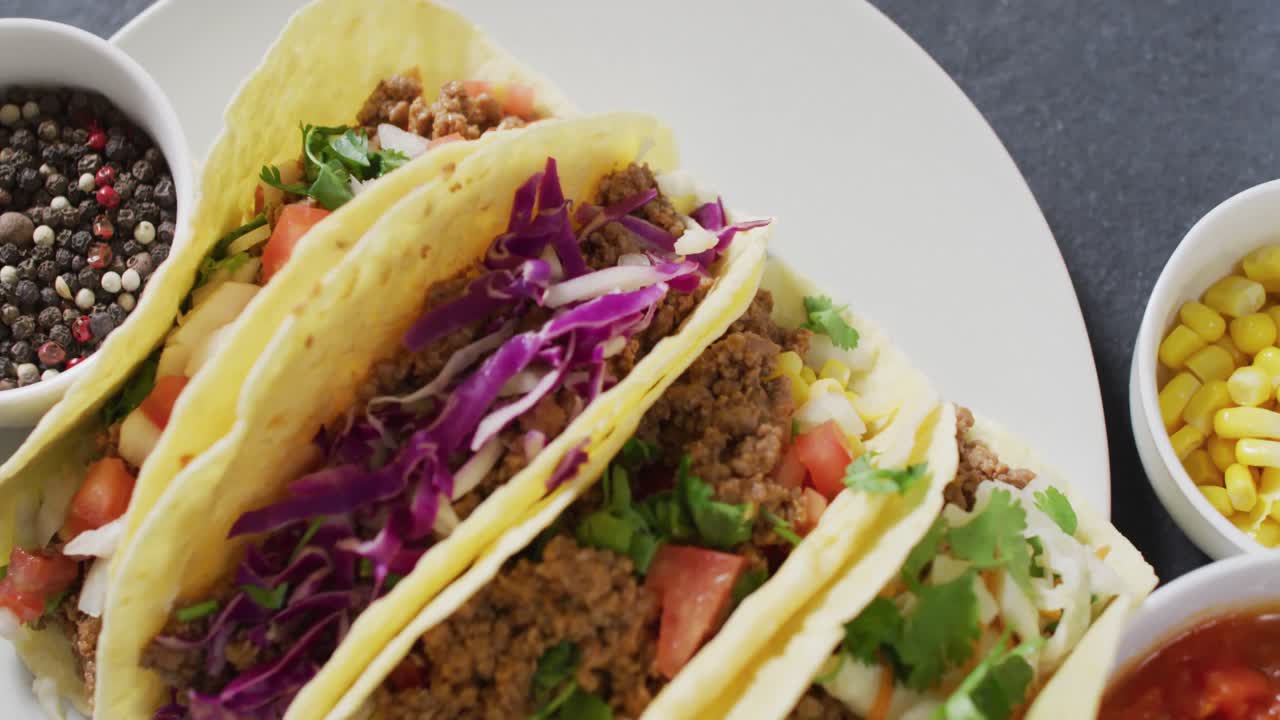video de tacos recién preparados en un plato sobre un fondo gris