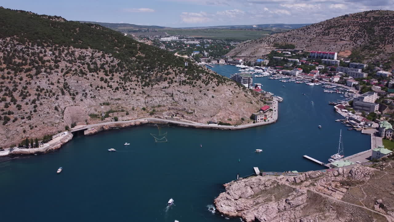 Aerial view of a picturesque bay with a marina and city nestled in the mountains