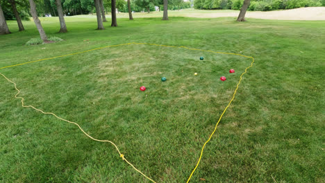 Overview-shot-of-locals-playing-traditional-boules-game-throwing-heavy-shiny-red-and-green-metal-balls-on-target