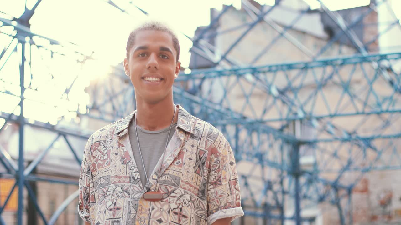 Happy hipster man looking at camera and smiling in the street