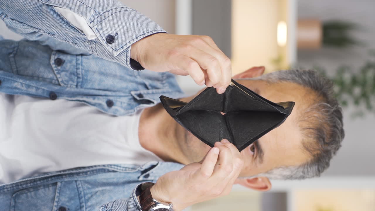 Vertical video of Penniless man looking at his empty wallet.