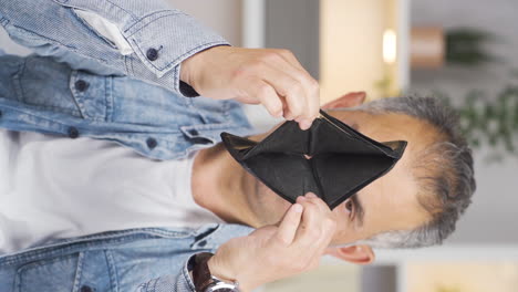 video vertical de un hombre sin dinero mirando su billetera vacía.