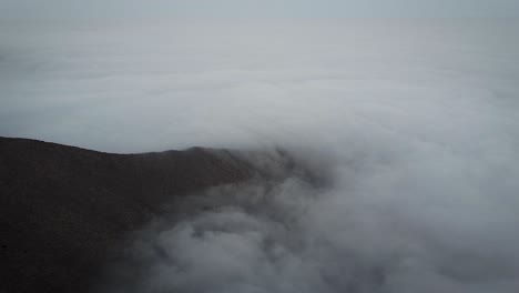 Absteigende-Drohnenaufnahme-Von-Nebel-An-Einem-Windigen-Tag-Auf-Einem-Berg-In-Lima,-Peru