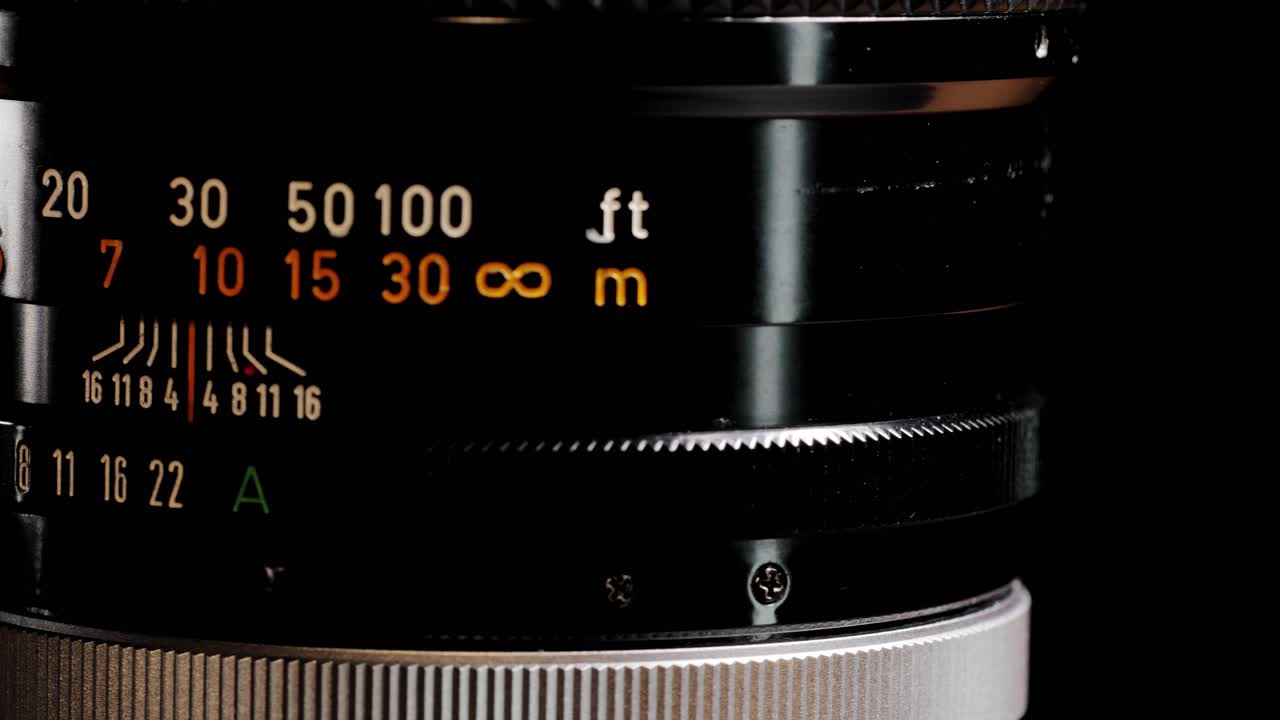 Rotating black vintage 135mm camera lens showing aperture and distance scale numbers