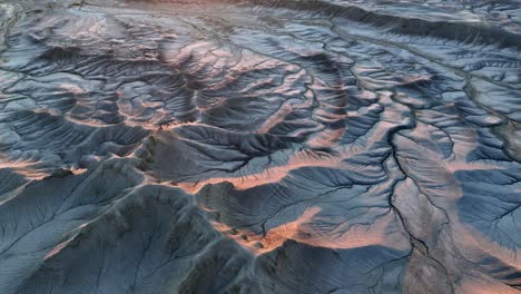 craters and river cracks in desert like mountain panorama during golden sunset