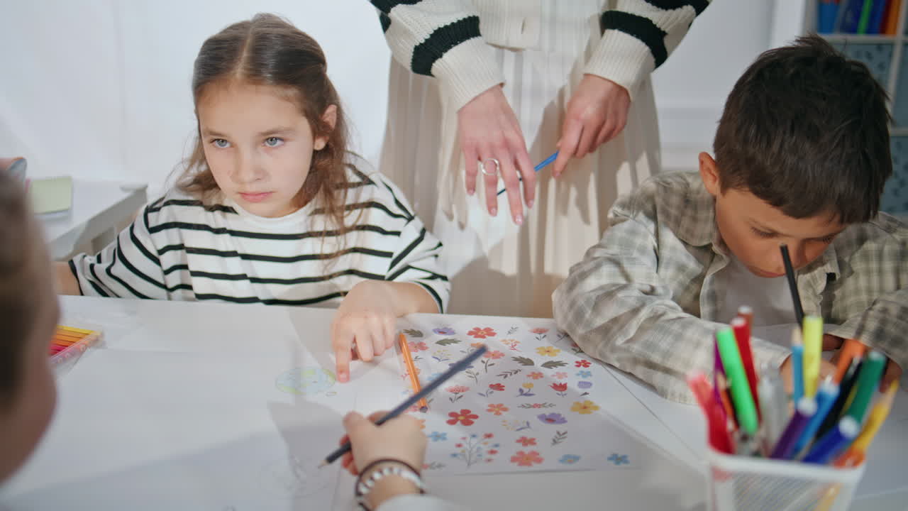 Small schoolchildren having art class at school closeup. Woman teacher helping