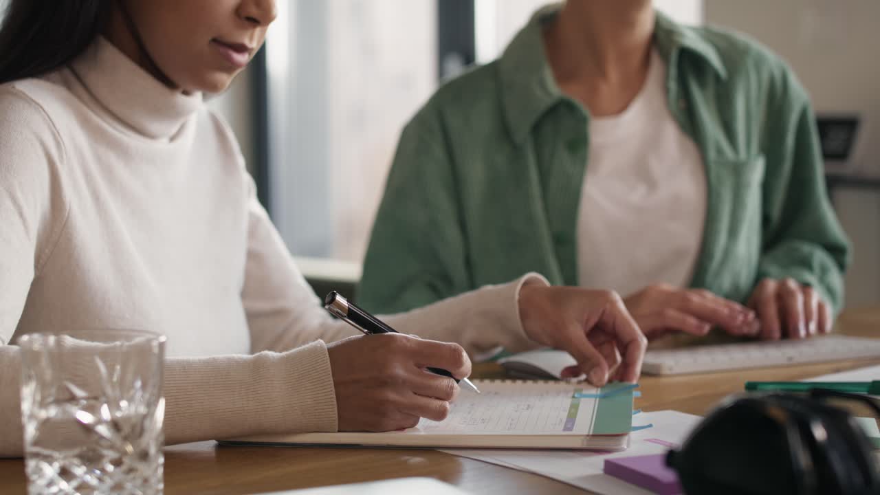 vista de bajo ángulo de dos mujeres trabajando en casa en notas y en la computadora