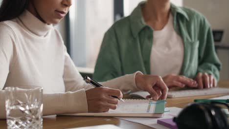 Low angle view of two women working at home in notes and on computer