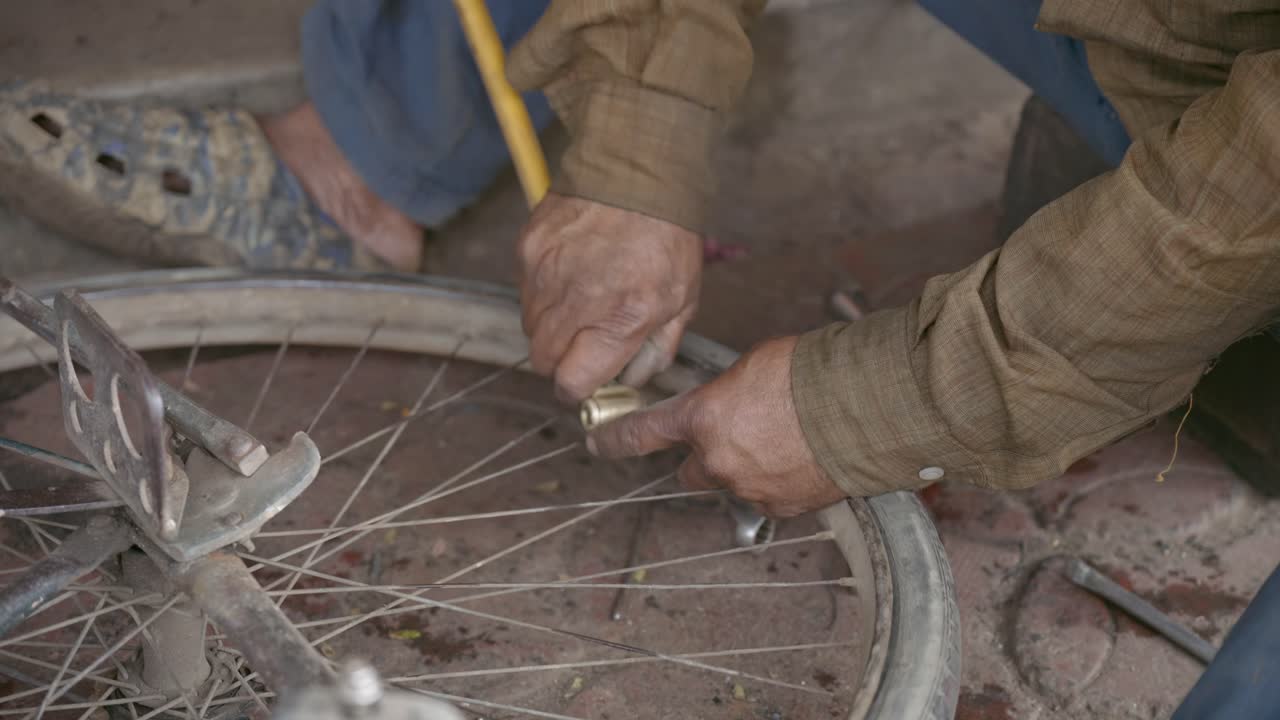 Close up of a local mechanics hands repairing a bicycle wheel or pumping air in tires on a summer street in India. Ideal for travel documentaries and lifestyle content