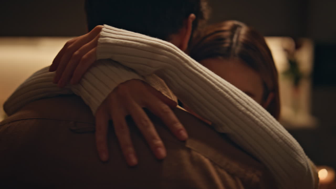 Esposa cariñosa abrazando al marido por el cuello bailando juntos en un apartamento oscuro, primer plano