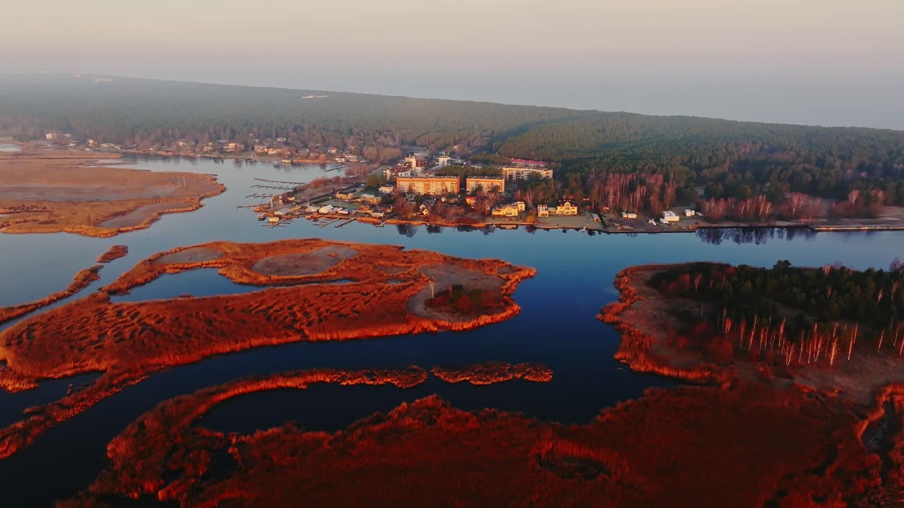 Early light reveals winding water and glowing wetland grasses near Lielupe river