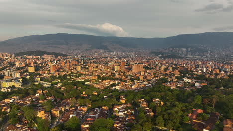 Aerial-view-circling-around-the-cityscape-of-Medellin,-golden-hour-in-Colombia