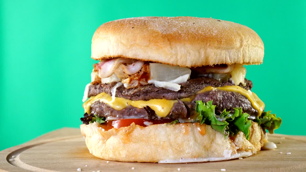 hamburguesa, con carne de res, queso y verduras gira sobre una tabla de madera.