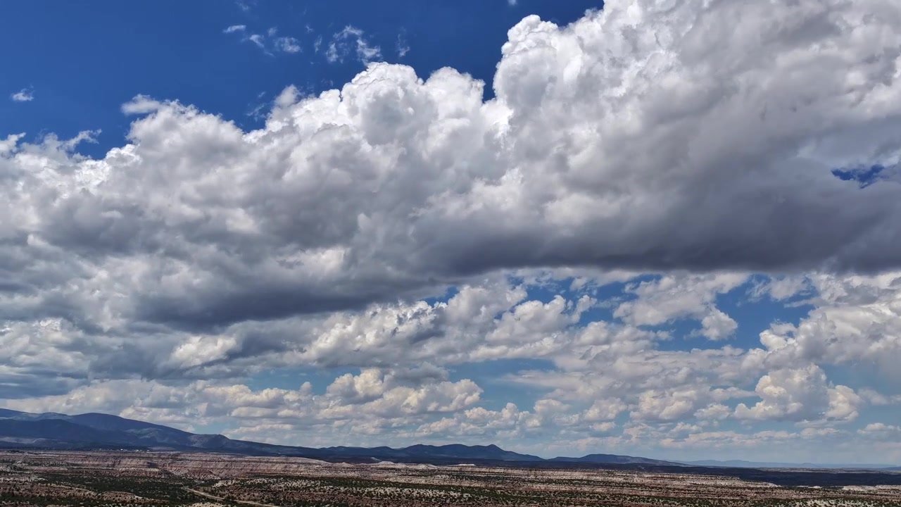4K UHD drone-timelapse, der fanger en betagende himmel fyldt med fantastiske rækker af teksturerede skyer. En massiv, skyggefuld skybanke driver jævnt over de tørre, lagdelte mesas i Sydvesten.