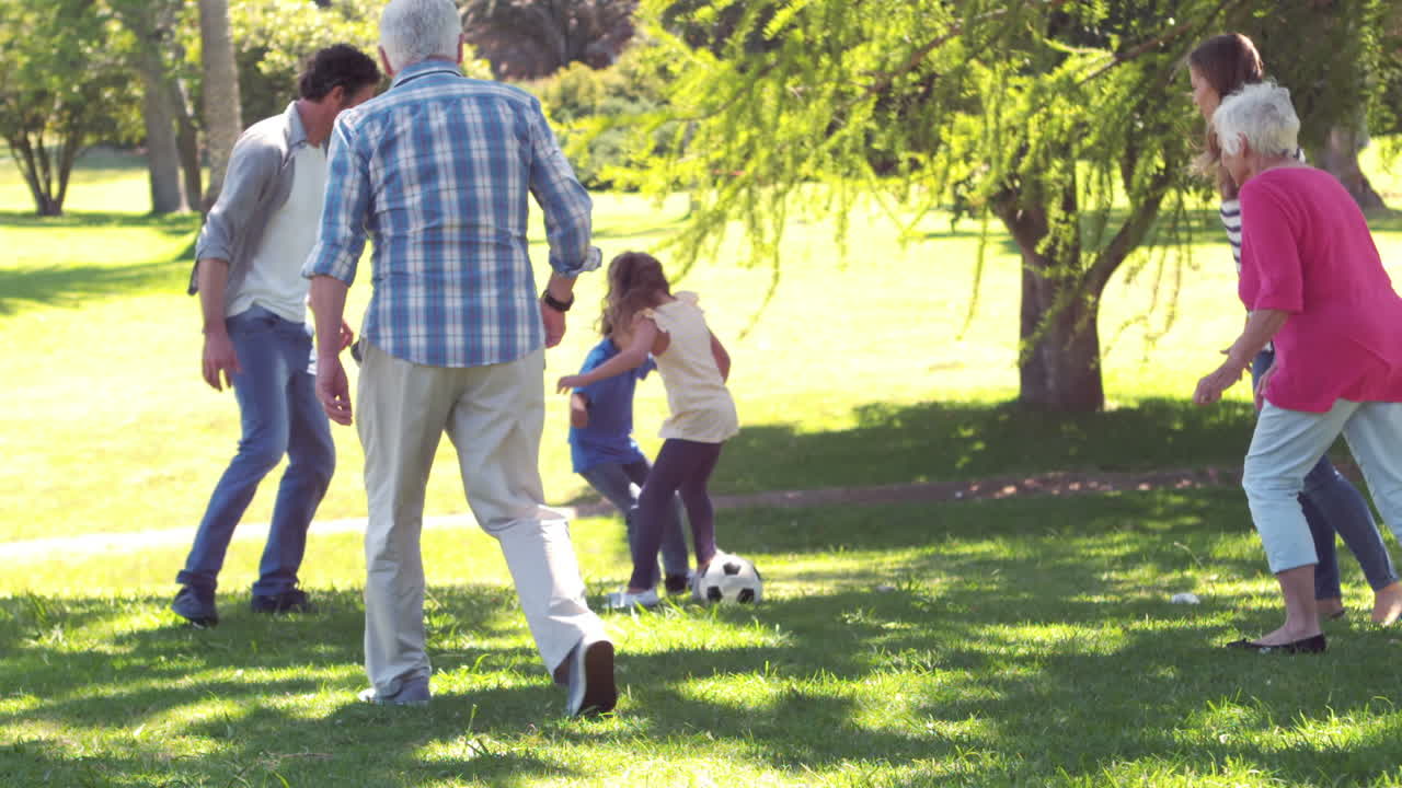 una alegre familia multigeneracional jugando al fútbol