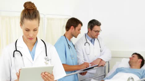 médicos hablando con pacientes enfermos en la cama mientras uno usa la tableta