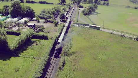 wide aerial view of a steam train leaving bodiam station, east sussex, england