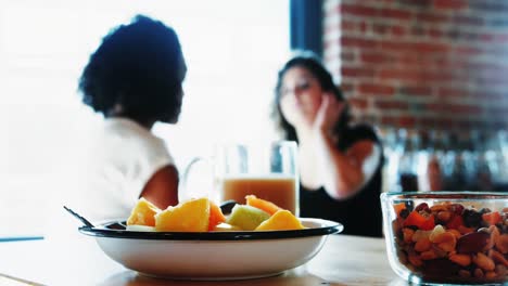 Close-up-of-breakfast-on-table-while-lesbian-couple-interacting-in-background