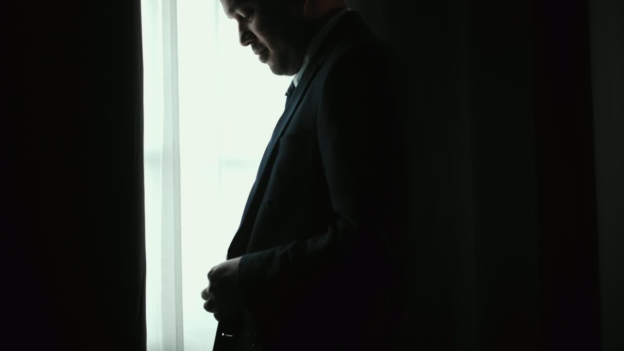 자신감있는 사업가 호텔 방의 창문 근처에 타이와 함께 고전적인 파란색 슈트를 조정합니다. 결혼식 날에 좋은 슈트를 입은 잘생긴 남자.