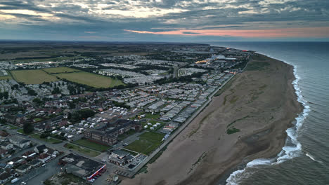 Drone-video-captures-Skegness-seaside-at-sunset,-featuring-holiday-park,-caravans,-and-sweeping-beach-views