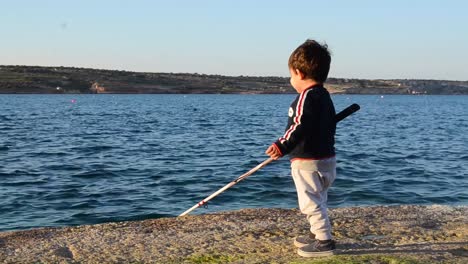 Un-Niño-Lindo-Que-Aprende-A-Usar-Una-Caña-De-Pescar-En-La-Costa-Rocosa-De-Malta