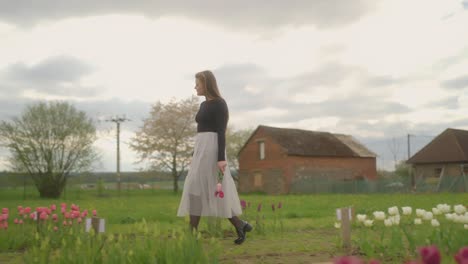 Field-of-flowers,-building-background,-surrounding-nature,-young-woman