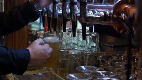 barman pouring pint of beer from stainless steel tap