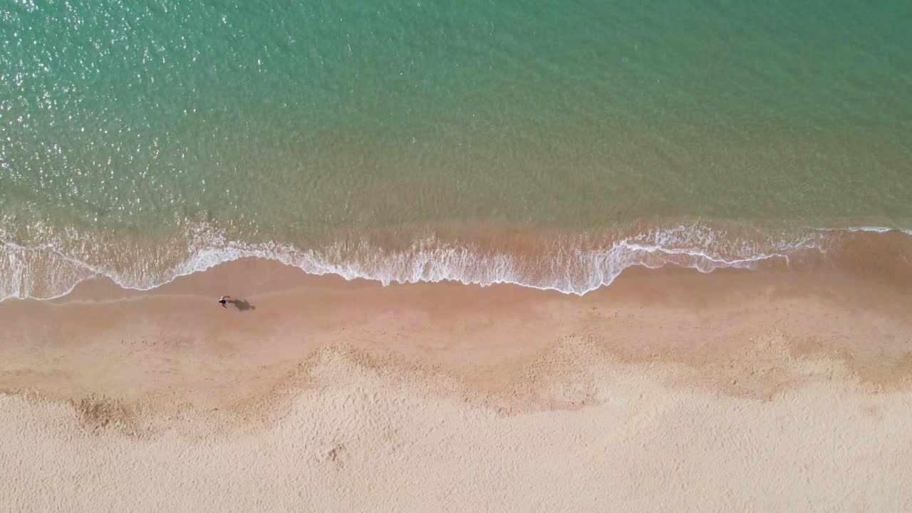 imágenes aéreas de drones de 4k de una persona caminando en una playa en coma-ruga