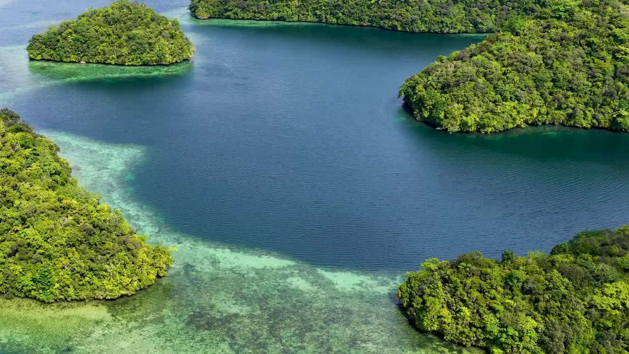 Høytliggende dronebilde som glir over tropiske kalksteinsøyer og turkise laguner i Mikronesia.